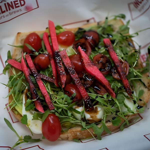 Inclined Burgers and Brews Caprese toast with arugula, cherry tomatoes, mozzarella, and balsamic glaze.