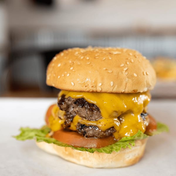 Inclined Burgers and Brews' double cheeseburger with melted cheese, lettuce, and tomato on a sesame bun.