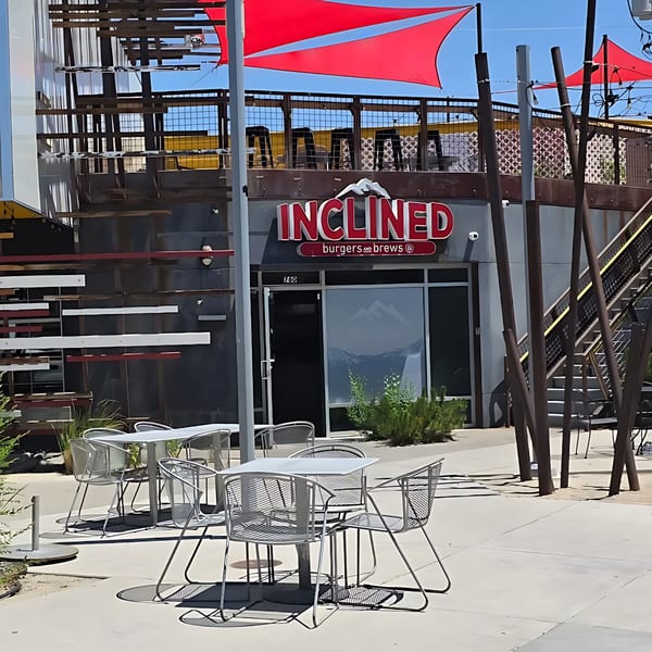 Inclined Burgers and Brews restaurant exterior with red awnings, outdoor seating, and a mountain logo.