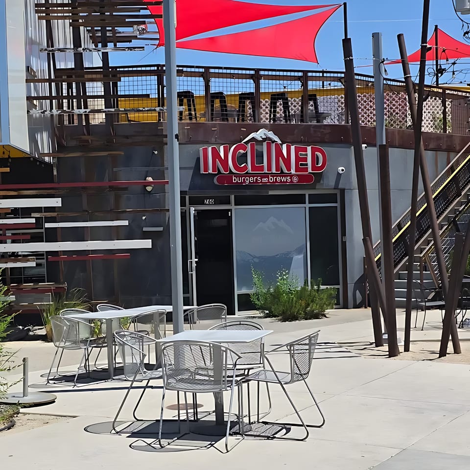 Inclined Burgers and Brews restaurant exterior with red awnings, outdoor seating, and a mountain logo.
