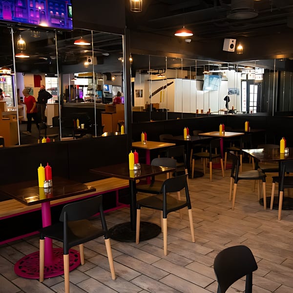 Modern Inclined Burgers and Brews dining room with black tables, chairs, and booths, featuring condiment bottles.