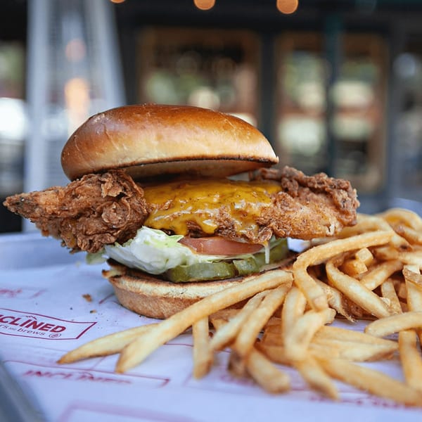 Inclined Burgers and Brews' fried chicken sandwich with cheese, lettuce, tomato, pickles, and fries.